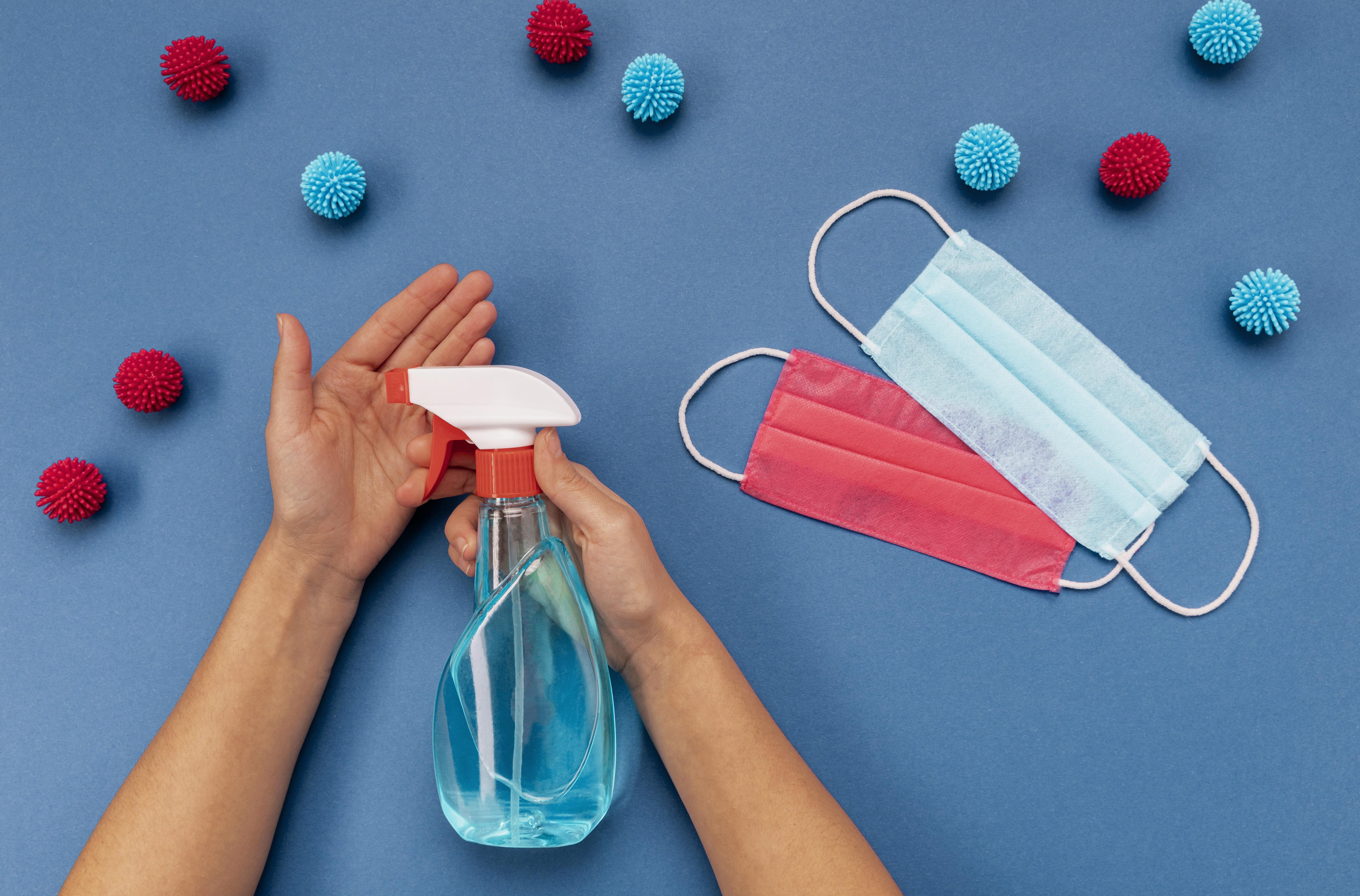 flat-lay-person-disinfecting-hands-near-medical-masks